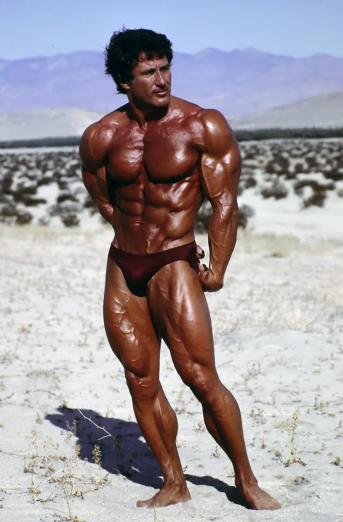 A striking desert most-muscular pose reveals crisp vein and muscle detail against a bleak, magazine-cover backdrop.