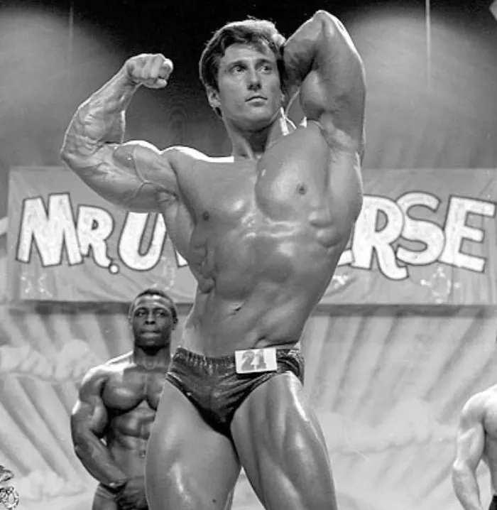 An early-career on-stage shot with the Mr. Universe banner visible behind him.