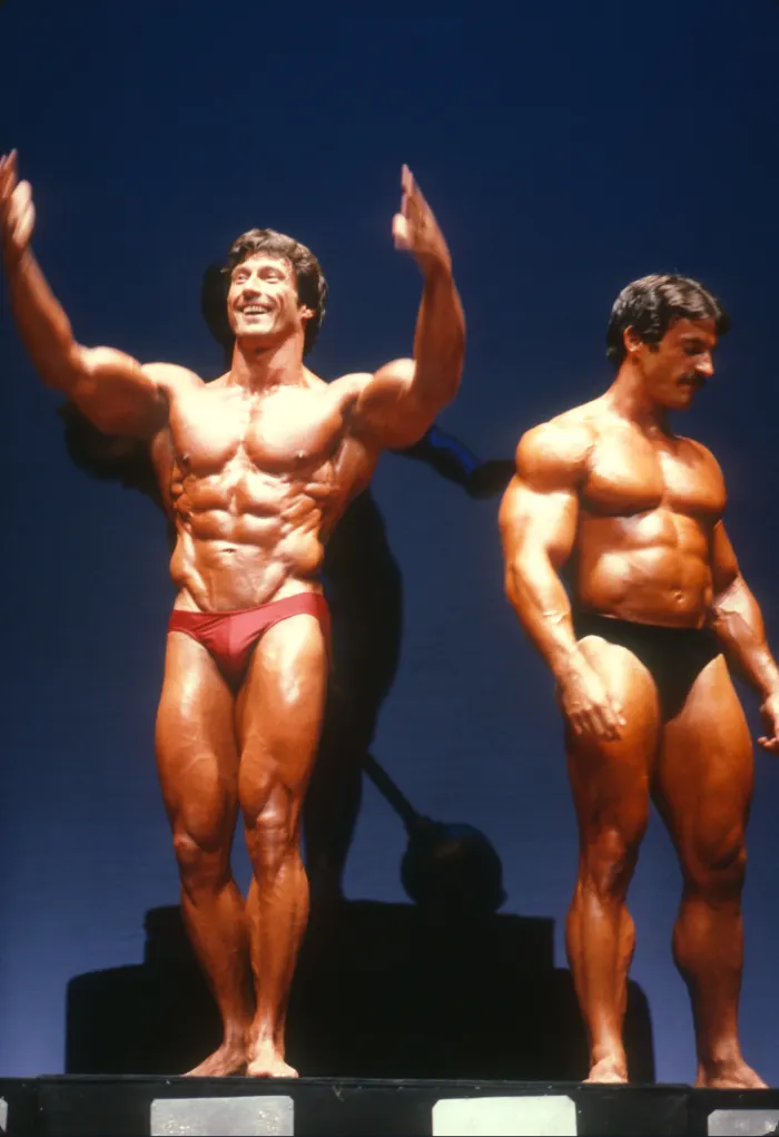 A candid victory moment, waving to the crowd alongside a fellow competitor.