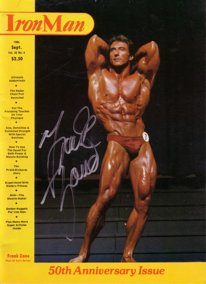 A signed IronMan 50th Anniversary Issue cover, contest-condition back double-biceps under stage lighting.