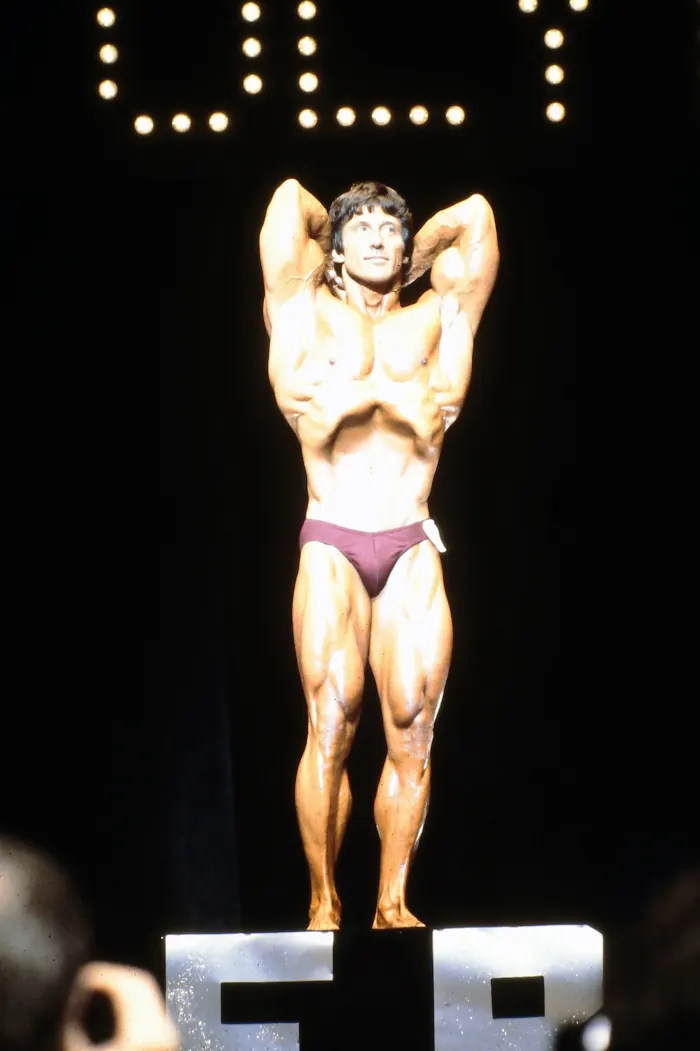 A most-muscular pose on the competition podium under bright lighting.